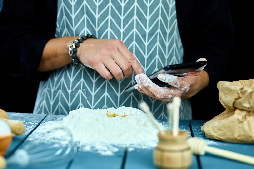 Person Checking Smartphone for Baking Recipe